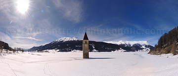 panorama: the old church tower in frozen lake resia