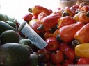 tropical fruit stand: green mangos (mangifera indica), cashew nuts (anacardium occidentale) and a broken knife